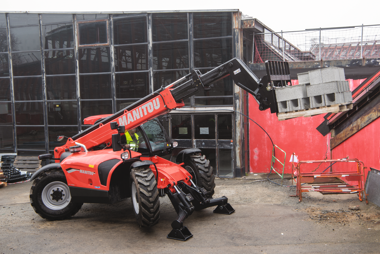 Manitou construction telehandler lifting concrete blocks on a construction site