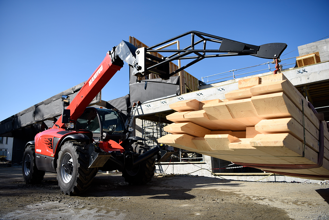 Manitou telehandler with jib attachment moving wood